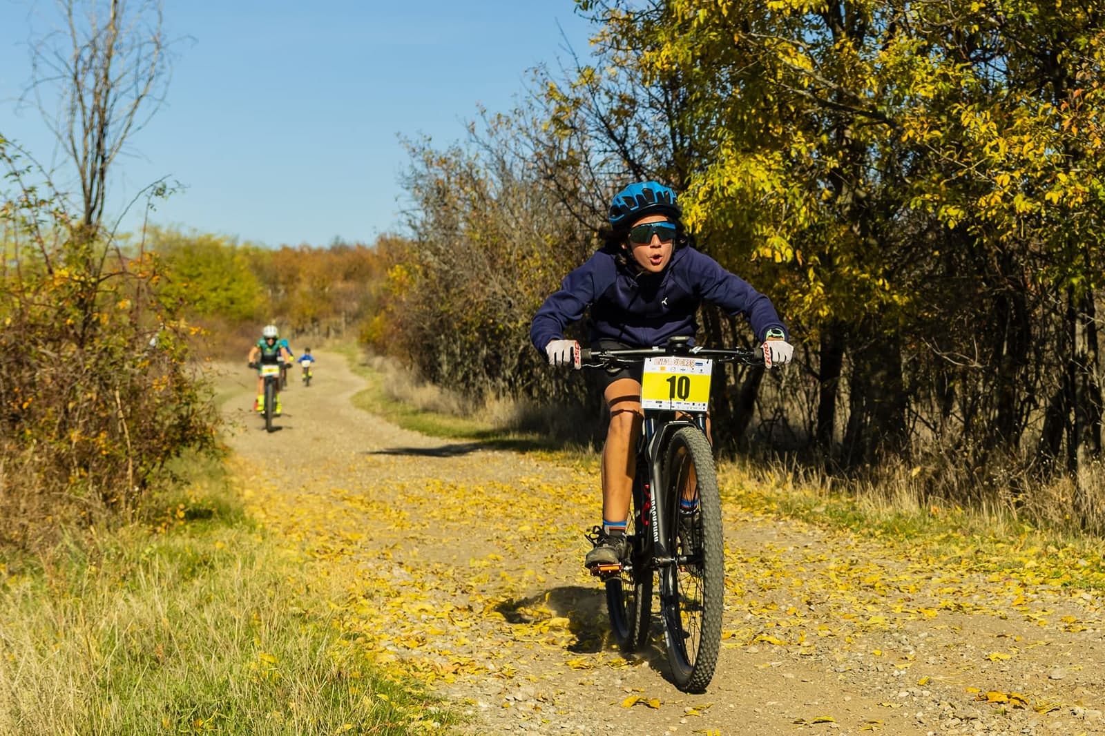 Copii în cursă de mountain bike cross-country, pe un traseu de toamnă